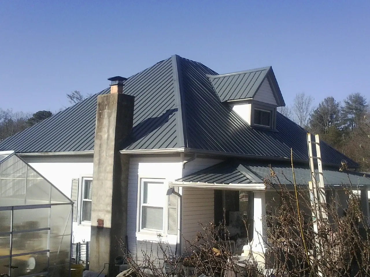 Dark blue standing seam metal roof on a white farmhouse with dormer — Slate & Tile Roof Repair by Roofing Brothers in Bonsall