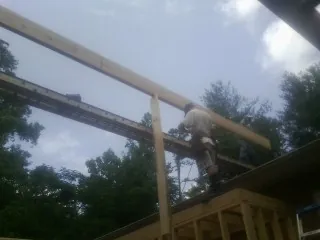 Carpenter setting a ridge beam over a new addition frame — Ice Dam Removal by Roofing Brothers in Bonsall