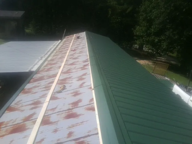 Old rusted panels beside newly installed green metal roofing — Wind Damage Roof Repair by Roofing Brothers in Bonsall