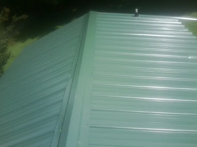 New green metal panels meeting at the ridge of a roof — Flat Roof Repair work by our crew in Bonsall