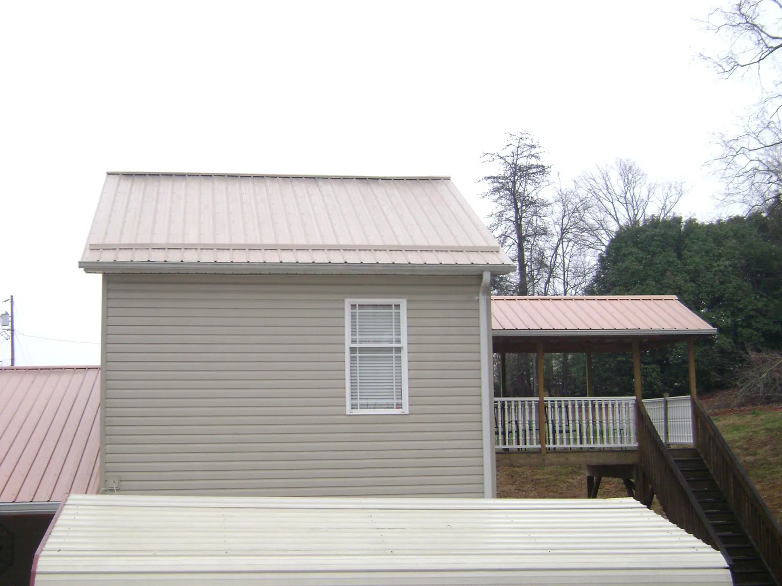Tan metal roofs on a two story addition and attached porch, from a Roof Replacement job in Bonsall