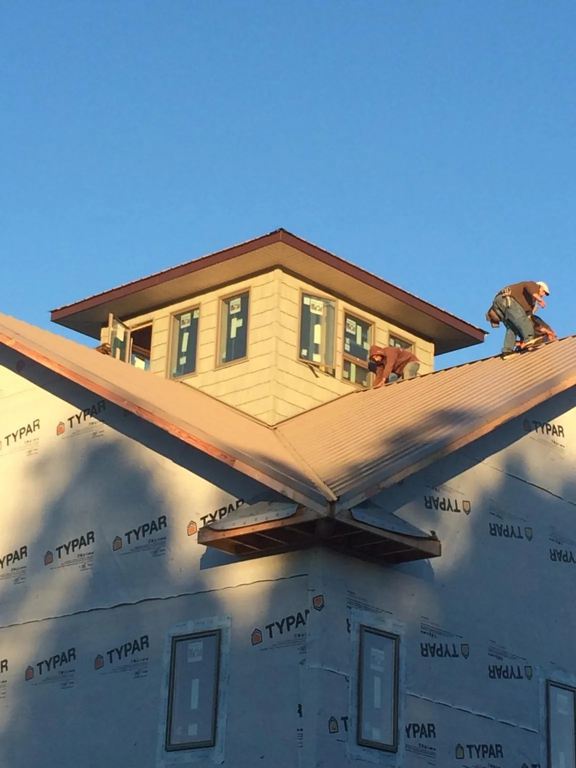 Roofers working around a rooftop cupola on a new metal roof at sunset — Roof Waterproofing in Bonsall by Roofing Brothers